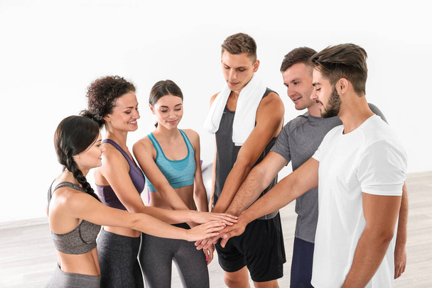 Концепция командной работы. Группа людей, делающих кучу рук в спортзале
 - Фото, изображение