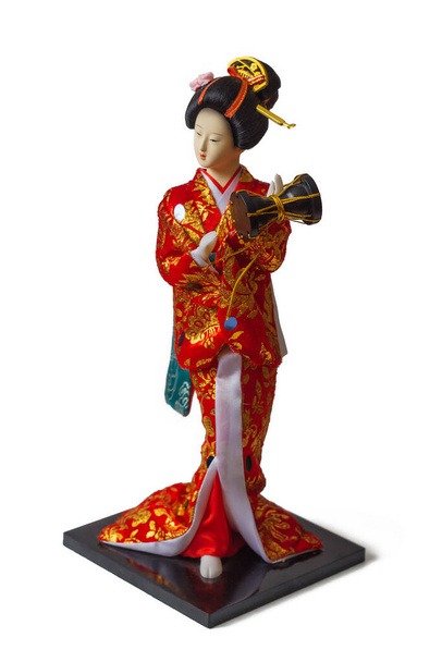 お土産人形-金で刺繍された赤い日本の着物の女の子。彼女は伝統的な髪型と手に茶色のドラムを持っています - 写真・画像