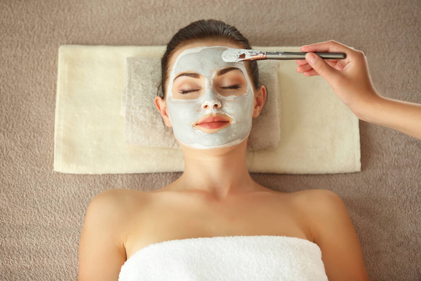 Concept de spa. Main appliquant un masque nourrissant sur le visage féminin dans le salon de spa
 - Photo, image