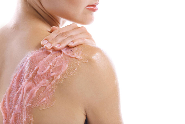 Young woman applying scrub on shoulder on white background - Photo, Image