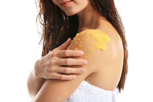 Young woman applying scrub on shoulder on white background - Photo, Image