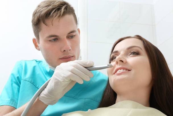 歯科用タービンを持つ男性歯科医と診療所で女性患者 - 写真・画像