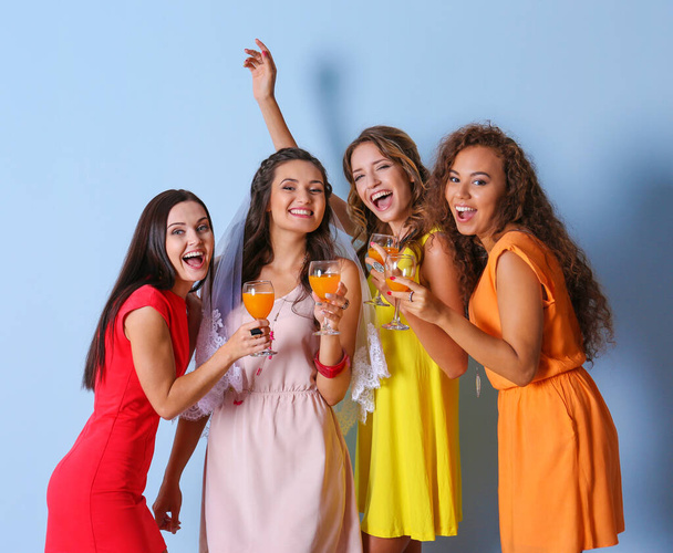 Beautiful girls with cocktails on blue wall background - Photo, Image