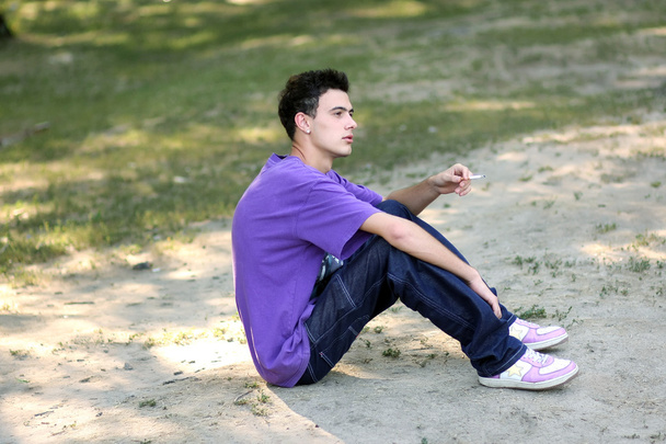 fiatal férfi-egy lila póló a cigarettát - Fotó, kép