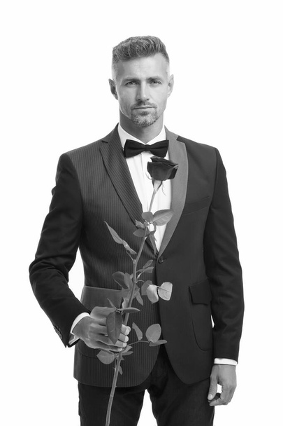 tuxedo man with rose flower. happy valentine day. special occasion. male formal style of clothing. elegant man in suit and tie sexy man on romantic date. Black tie dress code for evening events - Foto, Bild