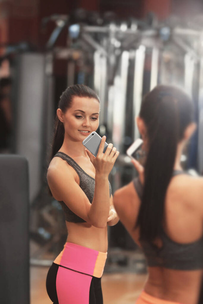 Jonge sportieve vrouw neemt selfie in de buurt spiegel in de sportschool - Foto, afbeelding