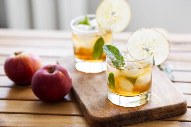 Apple juice with ice, mint and apple slice as garnish. Concept of refreshment drinks at sunny day. Blank for recipe of cocktail - 写真・画像