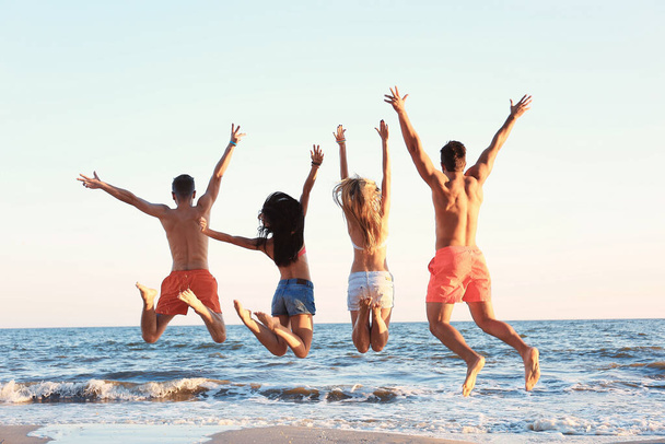 Amigos felizes pulando na praia
 - Foto, Imagem