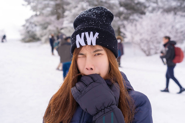 Funny beauty atractive woman with winter fashion clothing is making funny face in snow skii resort bitting her hand. - Photo, Image