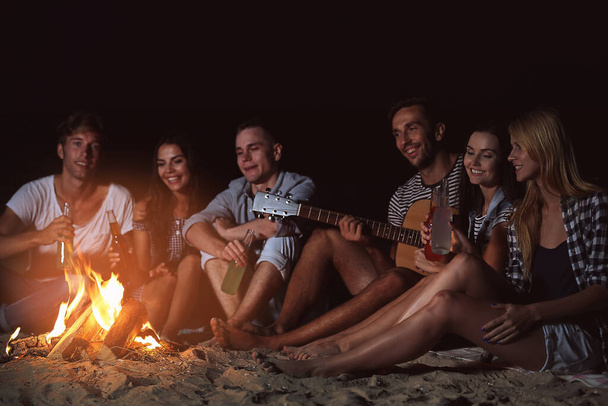 Happy friends near fireplace on the beach - 写真・画像