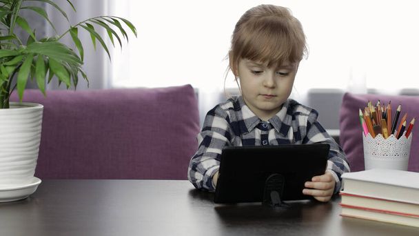 デジタルタブレットコンピュータを使用してオンライン宿題を勉強女の子。距離教育 - 写真・画像
