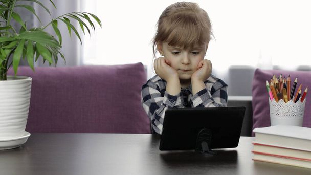 Tyttö opiskelee verkossa oppitunteja digitaalisen tabletin tietokoneella. Etäopetus
 - Valokuva, kuva