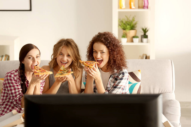 Women eating pizza and watching TV at home party - Foto, Imagem