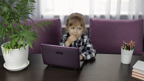 Tyttö opiskelee verkossa läksyjä digitaalisen kannettavan tietokoneen avulla. Etäopetus
 - Valokuva, kuva
