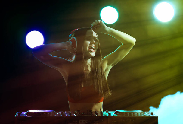 Jolie jeune DJ jouant de la musique en boîte de nuit
 - Photo, image