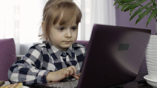 女の子は、デジタルラップトップコンピュータを使用してオンラインレッスンを学ぶ。距離教育 - 写真・画像