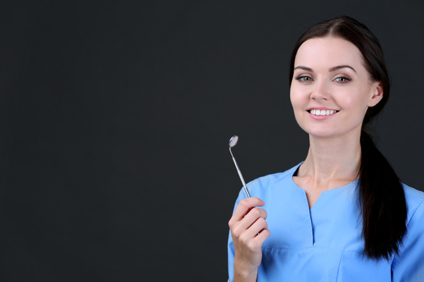 Dentista feminino com ferramenta em fundo cinza
 - Foto, Imagem