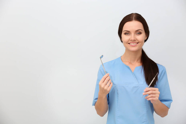 Dentista femenina con herramientas sobre fondo claro - Foto, Imagen