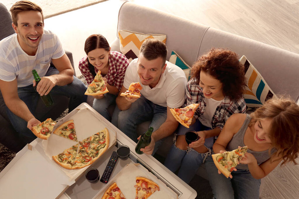 Vrienden die op de bank zitten en lekkere pizza eten - Foto, afbeelding