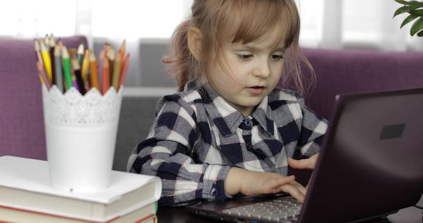 Tyttö tekee verkossa läksyjä digitaalisen kannettavan tietokoneen avulla. Etäopetus
 - Valokuva, kuva