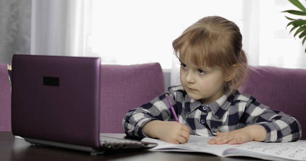 Κορίτσι κάνει μαθήματα στο σπίτι χρησιμοποιώντας ψηφιακό φορητό υπολογιστή. Εκπαίδευση εξ αποστάσεως - Φωτογραφία, εικόνα