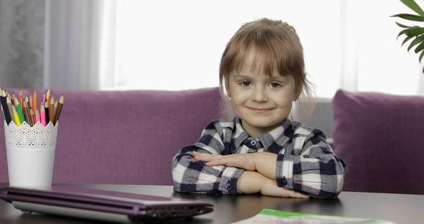 Девушка сидит на столе дома. Изучаю домашнее задание онлайн. Дистанционное образование
 - Фото, изображение