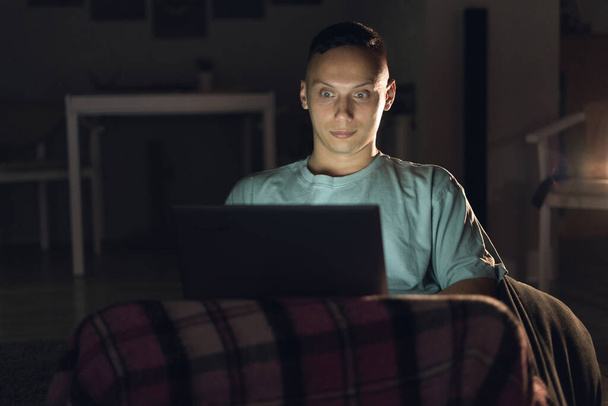 Un hombre solitario se sienta en casa por la noche y trabaja en línea. Ver una película antes de ir a la cama
. - Foto, imagen
