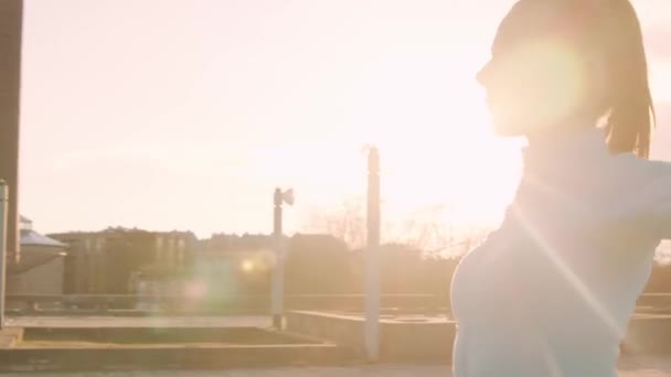 Young, beautiful and sporty woman having evening training outdoor. Urban sunset background. Fitness and sport concept. - Video