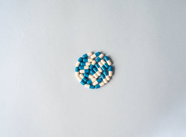 Medical therapeutic dissolving capsules of white and blue colors in the shape of a circle on a blue background. Top view. Copy space - Photo, Image
