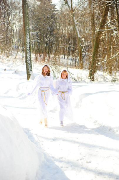 two girls with white hoodies with angel wings on a winter background - Foto, Imagem
