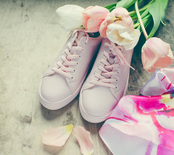 Woman pink sneakers and tulips flowers on a wooden background - Foto, Imagen