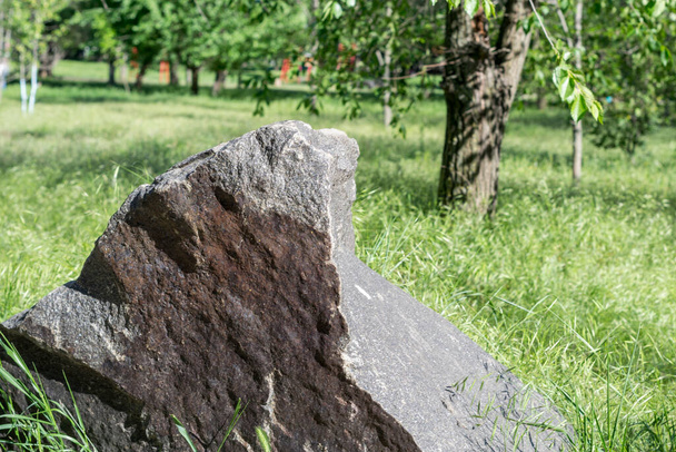 Grote granieten steen geïsoleerd op een grasveld. - Foto, afbeelding