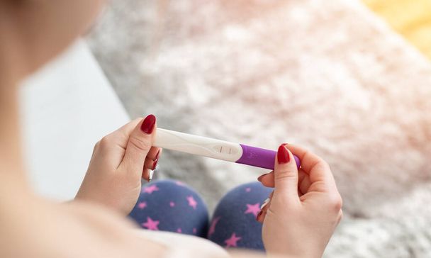 Young woman with pregnancy test in hands - 写真・画像