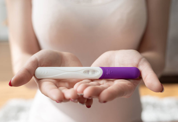 Close up of woman hand holding a positive home pregnancy test. - Foto, afbeelding