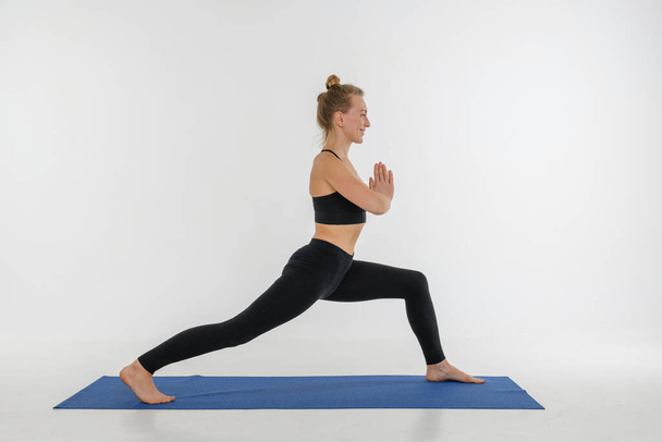 Sporty attractive young woman doing yoga practice on white background. Warrior, Virabhadrasana. - Photo, Image