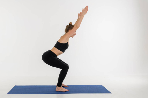Sportovní atraktivní mladá žena, která cvičí jógu na bílém pozadí. Kursiasana. - Fotografie, Obrázek