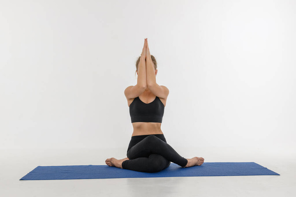 Sporty attractive young woman doing yoga practice on white background. Gomukhasana - Foto, immagini
