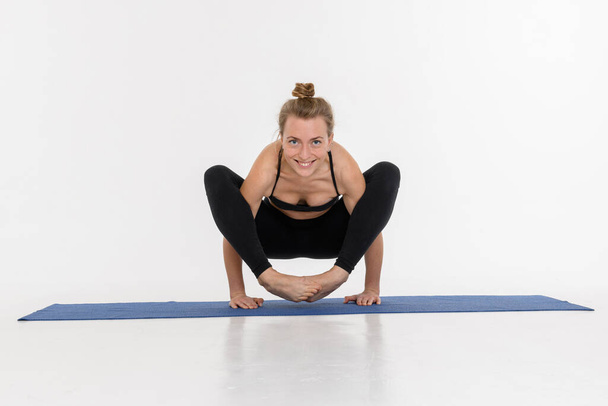 Sporty attractive young woman doing yoga practice on white background. - 写真・画像