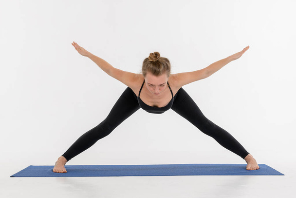 Sportlich attraktive junge Frau praktiziert Yoga auf weißem Hintergrund. - Foto, Bild