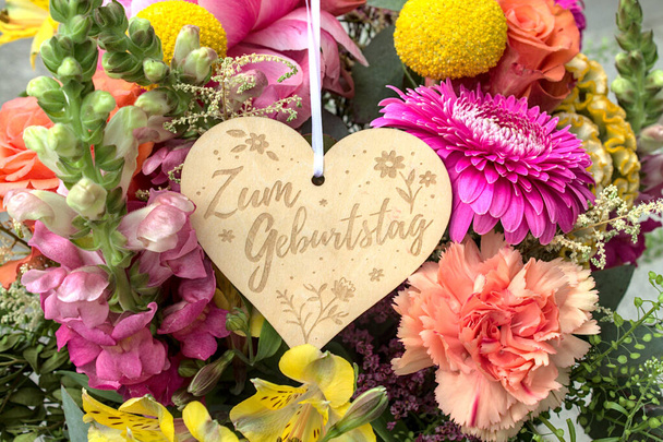 bos bloemen en een houten hart met de Duitse tekst voor de verjaardag  - Foto, afbeelding