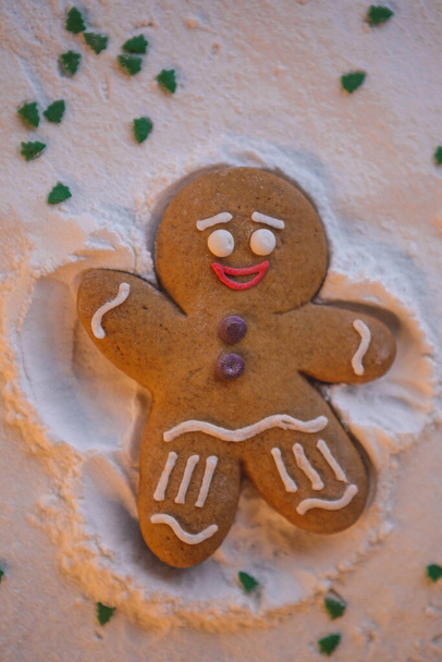 Καλή Χρονιά: ο κοκκινοτρίχης ξαπλωμένος στο έδαφος και με τη βοήθεια των χεριών και των ποδιών του κάνει το σχήμα ενός αγγέλου να αφήνει ένα αποτύπωμα στο χιόνι - Φωτογραφία, εικόνα