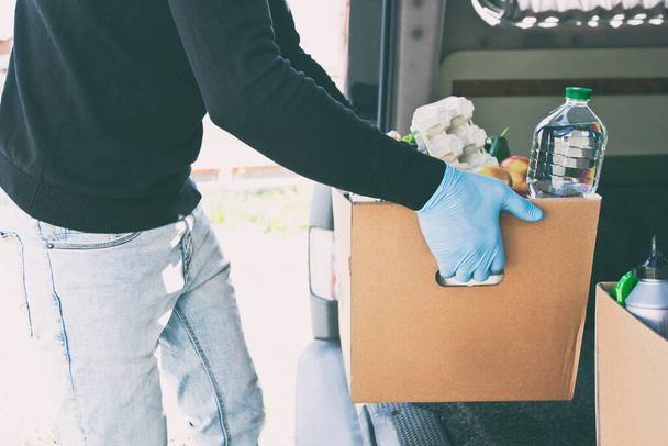 El mensajero saca la caja ecológica de cartón con productos de la tienda de comestibles de la furgoneta - Foto, imagen