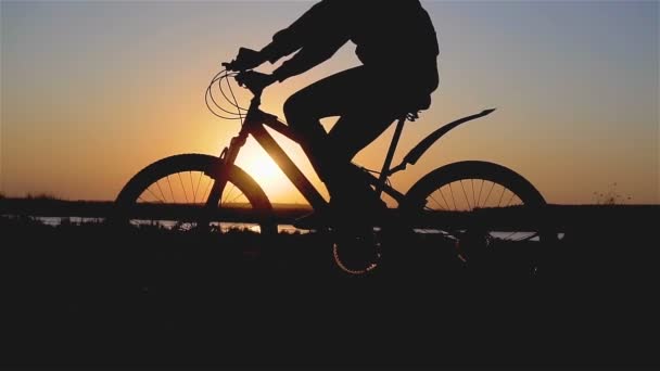Mooie lente stemming schot van jonge vrouw of meisje rijden fiets door rivier strand en pedalen in de avond zonsondergang licht - Video