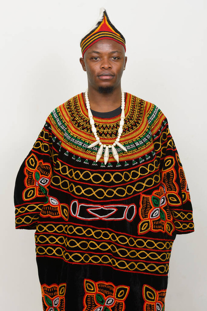 Beyaz arka planda geleneksel kıyafetler giyen yakışıklı Afrikalı genç adamın stüdyo fotoğrafı. - Fotoğraf, Görsel