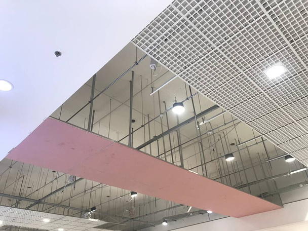 Macro Grid Valse plafond rond gips afgewerkt onder de uitvoering die roze gipsplaat furring kanalen ondersteunt en schroefdraad bloot - Foto, afbeelding