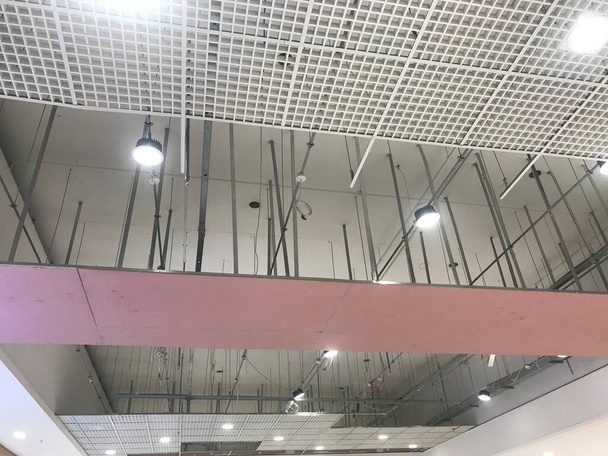 Makro Mřížka Falešný strop kolem sádry dokončen v průběhu, které odhalují růžové sádrokartonové desky furring kanály podpěry a závitové tyče - Fotografie, Obrázek