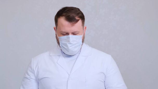 Male in a protective mask and a white shirt head bowed. Hygiene concept. prevent the spread of germs and bacteria and avoid infection with the crown virus. copy space - Photo, Image