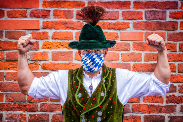 bavarian man flexing his muscles and wearing a protective blue white mask - Fotografie, Obrázek