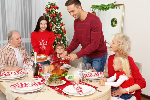 Ευτυχισμένη οικογένεια που έχει Χριστουγεννιάτικο δείπνο στο σαλόνι - Φωτογραφία, εικόνα