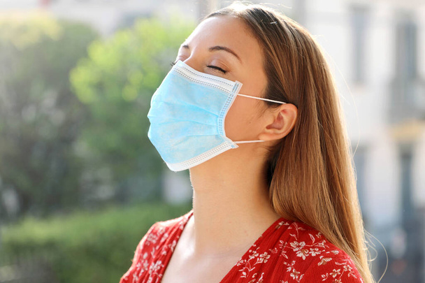 COVID-19 Пандемия коронавируса Закрыть молодую женщину с хирургической маской дыхание на открытом воздухе
 - Фото, изображение